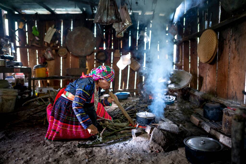 Woman cooking on a smoky traditional stove, showing why clean cooking programs are needed